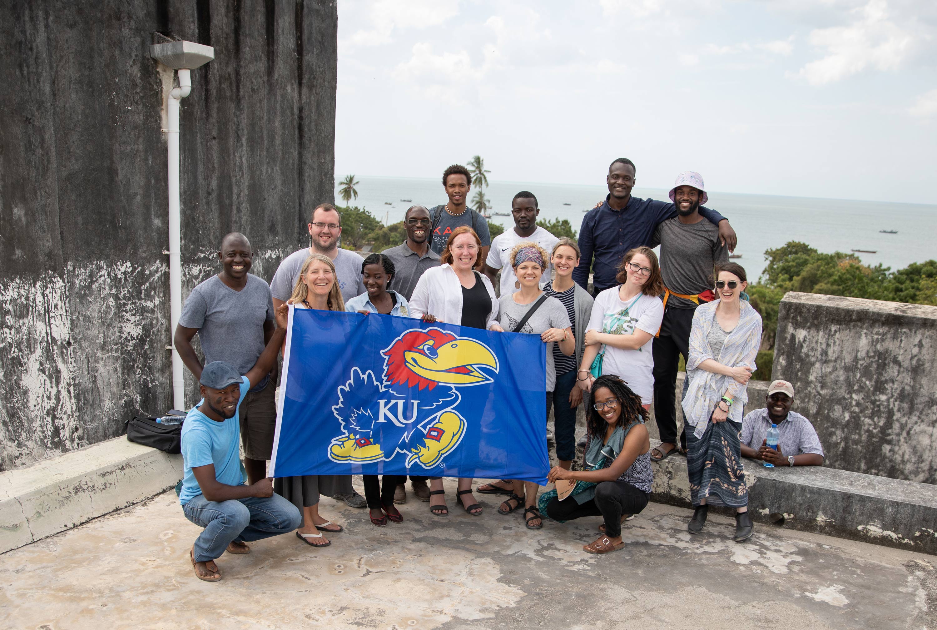 A group of people pose for a photo holding a KU flag in Tanzania